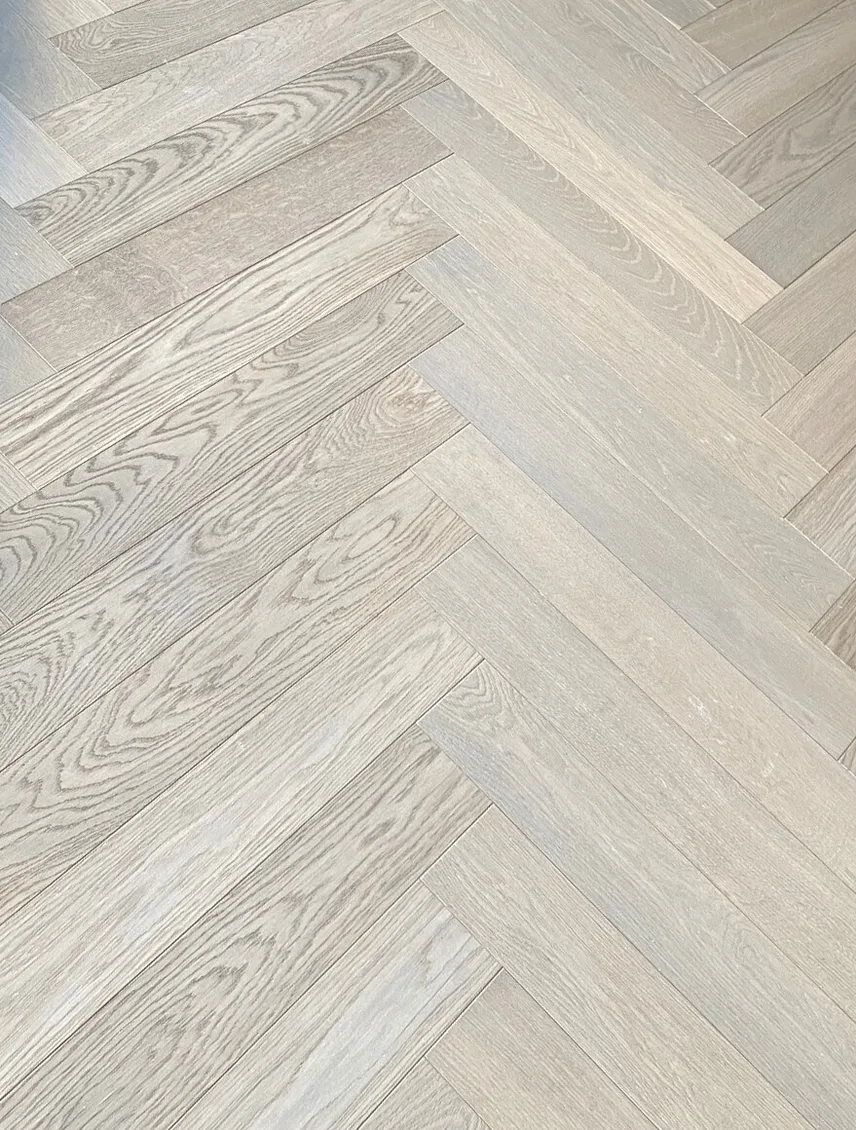 Detailní pohled na světlou dubovou podlahu z kolekce Ivory položenou do klasického vzoru stromečku (herringbo