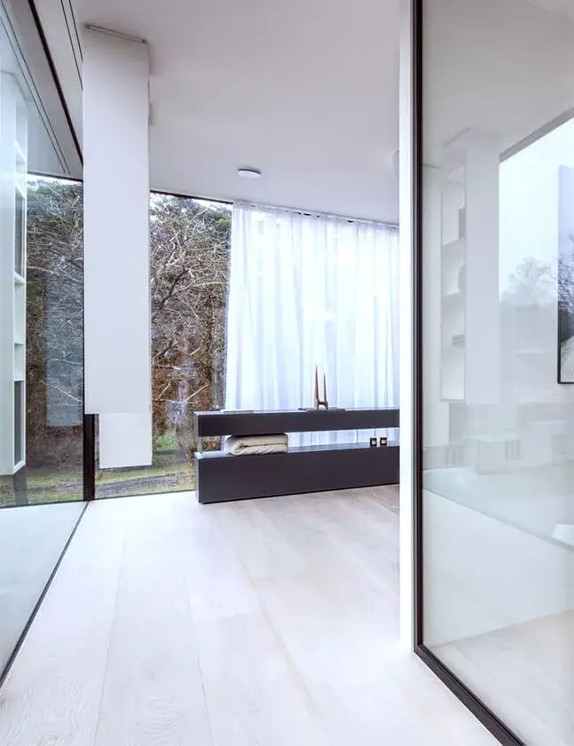 Minimalistický interiér Lago Showhouse se světlou dubovou podlahou Oakcent v běleném dekoru, který v kombinaci s velkoformátovým prosklením a bílými závěsy vytváří vzdušný, čistý prostor propojený s okolní přírodou.