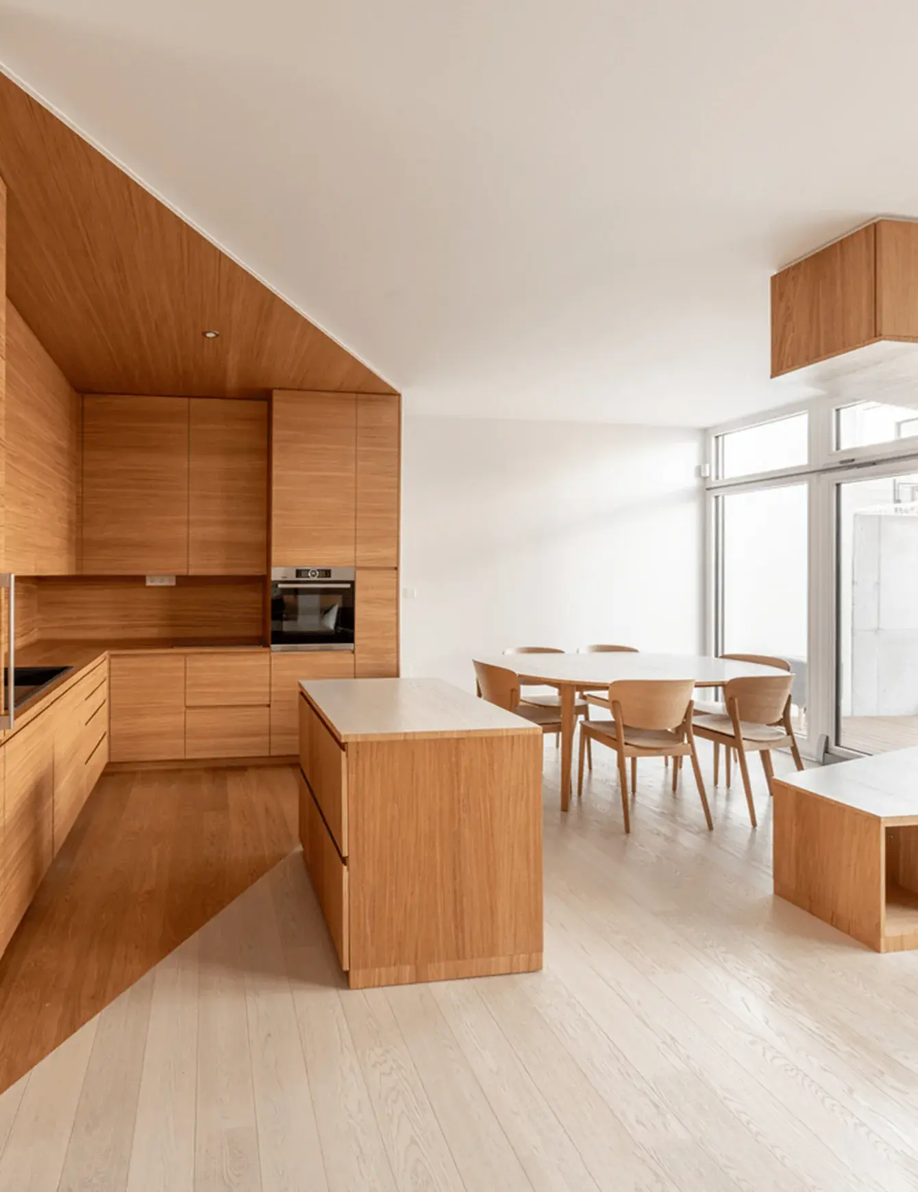 Moderní minimalistický interiér v projektu Ke Káčatům v Brně, kde se setkávají dvě barvy dubové podlahy Oakcent – medový odstín v kuchyňské zóně a světlý dekor v jídelně – oddělené precizním diagonálním spojem, který sleduje linii dřevěného nábytku.