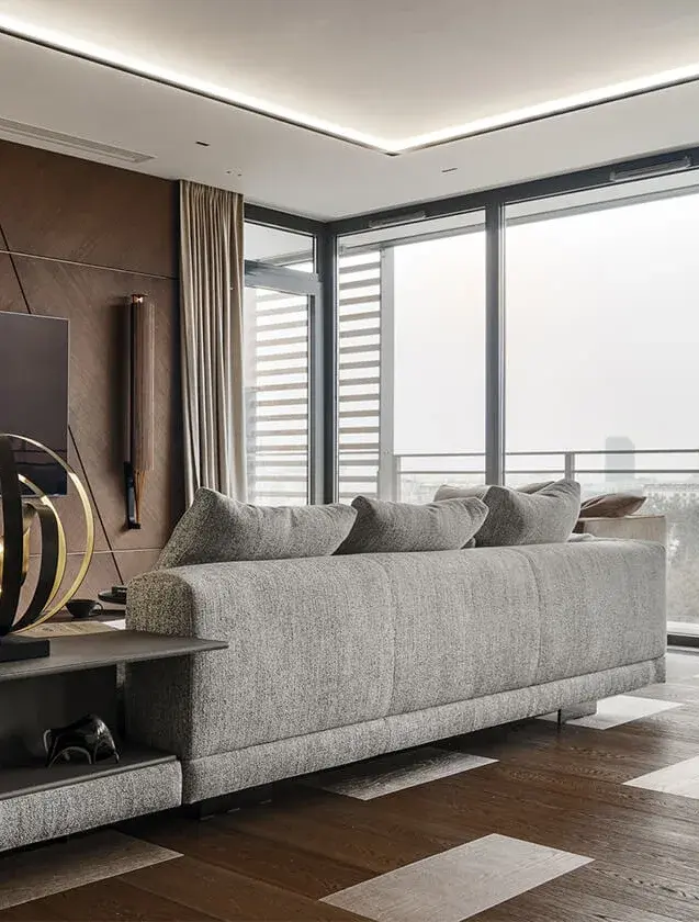 Moderní a sofistikovaný obývací pokoj v centru Varšavy s šedou texturovanou pohovkou na tmavé dubové podlaze Oakcent, která je v geometrickém kontrastu se světlými kamennými poli pod prosklenou stěnou.