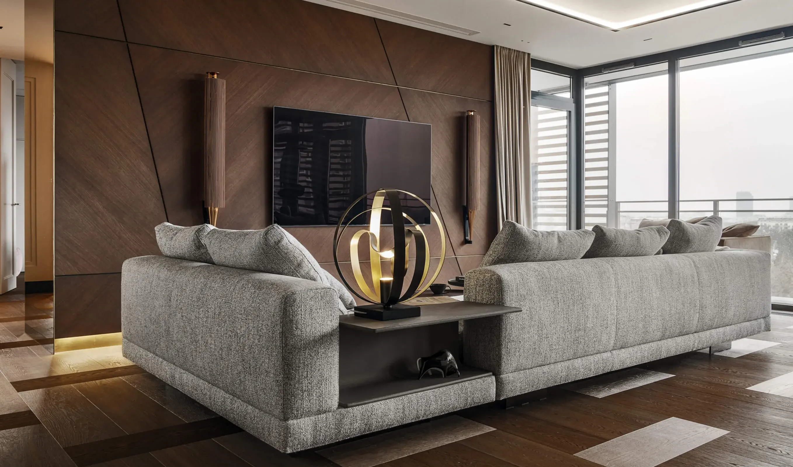 Detailní pohled na obývací pokoj v bytě Grzybowska, kde se propojují různé materiály a geometrie; tmavá dubová podlaha Oakcent s vloženými světlými poli plynule navazuje na dřevěné obklady stěn s diagonálním členěním a luxusní designový nábytek.