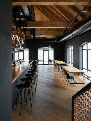 Široký pohled na bar návštěvnického centra Bernard s masivním dřevěným krovem, tmavými stěnami a odolnou dubovou podlahou Oakcent v restauraci.