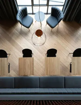 Pohled z ptačí perspektivy na diagonální pokládku dubové podlahy Oakcent v interiéru restaurace Bernard s designovými křesly a stolky.