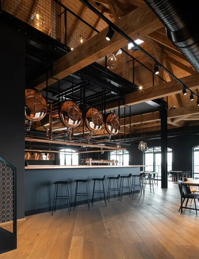 Široký pohled na bar návštěvnického centra Bernard s měděnými pivními tanky, masivním dřevěným krovem a odolnou dubovou podlahou Oakcent, která sjednocuje industriální prostor restaurace.