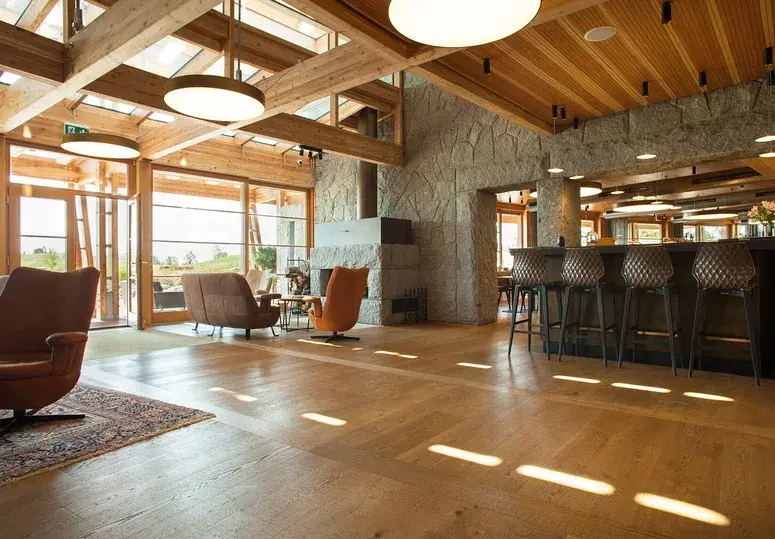 Moderní barový kout v rezidenci s prošívanými barovými stoličkami, kamenným obkladem a širokými dubovými prkny Oakcent