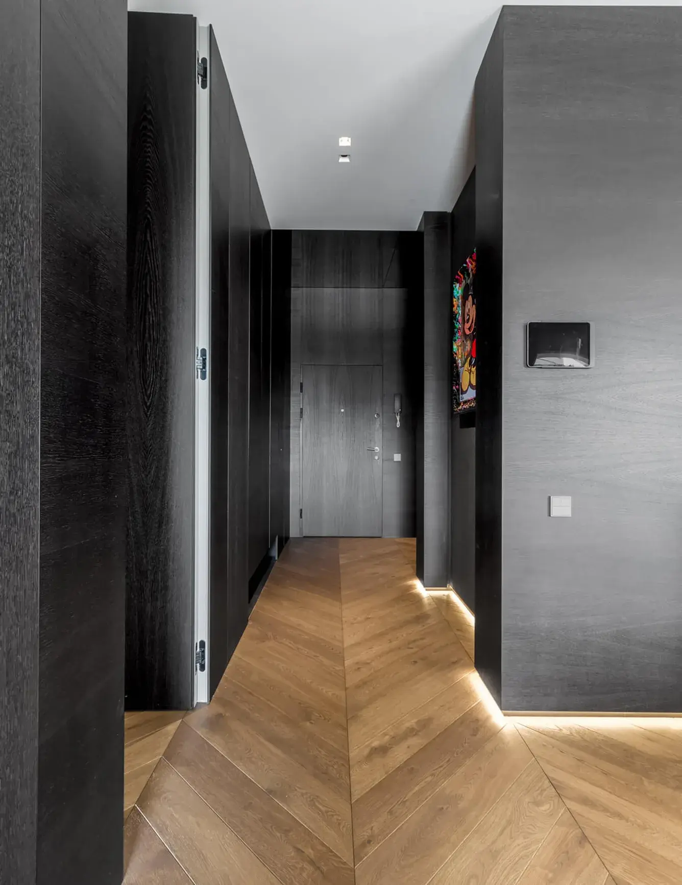 Pohled na kuchyňský ostrůvek s patinovaným efektem a zrcadlovým soklem, který odráží podlahu Oakcent Rustic Chevron v varšavském interiéru.