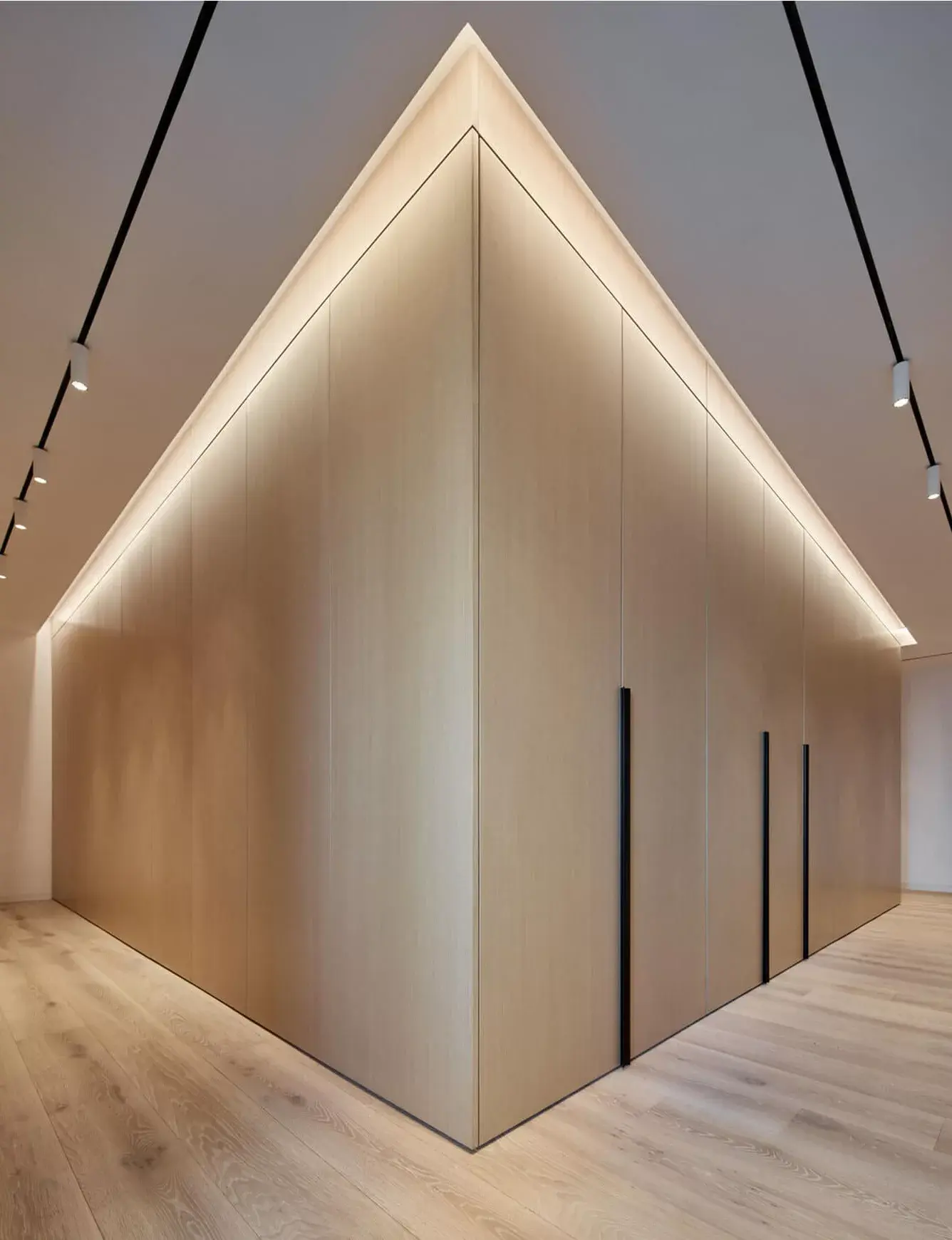 Alt text: Pohled na minimalistickou vestavnou skříň s nepřímým LED osvětlením a vysokou dubovou podlahu Oakcent Rustic v Bianco oleji, sjednocující moderní interiér bytu s výhledem na Žižkovskou věž.