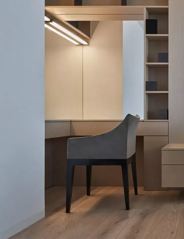 Interiér šatny v moderním pražském bytě s designovým toaletním stolkem a šedým křeslem, kde světlé tóny nábytku harmonicky doplňuje dubová podlaha Oakcent z kolekce Sand.