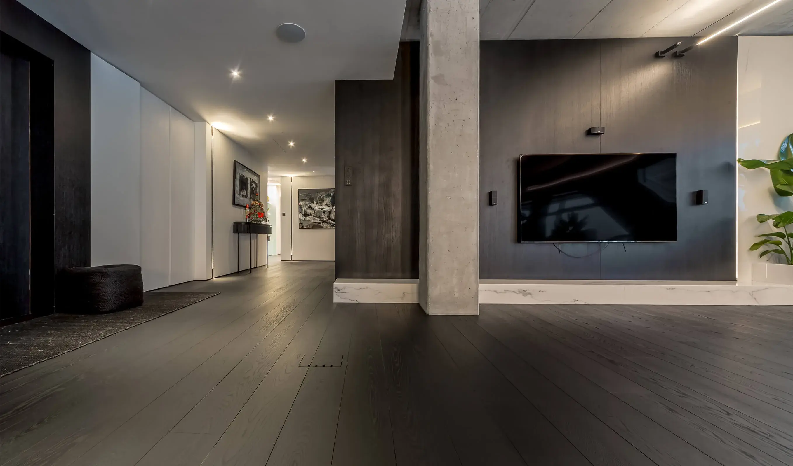 Detailní pohled na tmavou dubovou podlahu Oakcent Premium v odstínu Super Graphite z kolekce INK, jejíž kartáčovaný matný povrch elegantně vyplňuje prostorný interiér apartmánu Złota 44 a plynule navazuje na betonové a mramorové prvky.