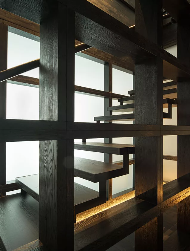 Detailní pohled na moderní dřevěné schodiště a nosnou konstrukci v sytě černém dekoru z kolekce Ink, doplněné integrovaným LED podsvícením, které zvýrazňuje hloubku a texturu tmavého dřeva.