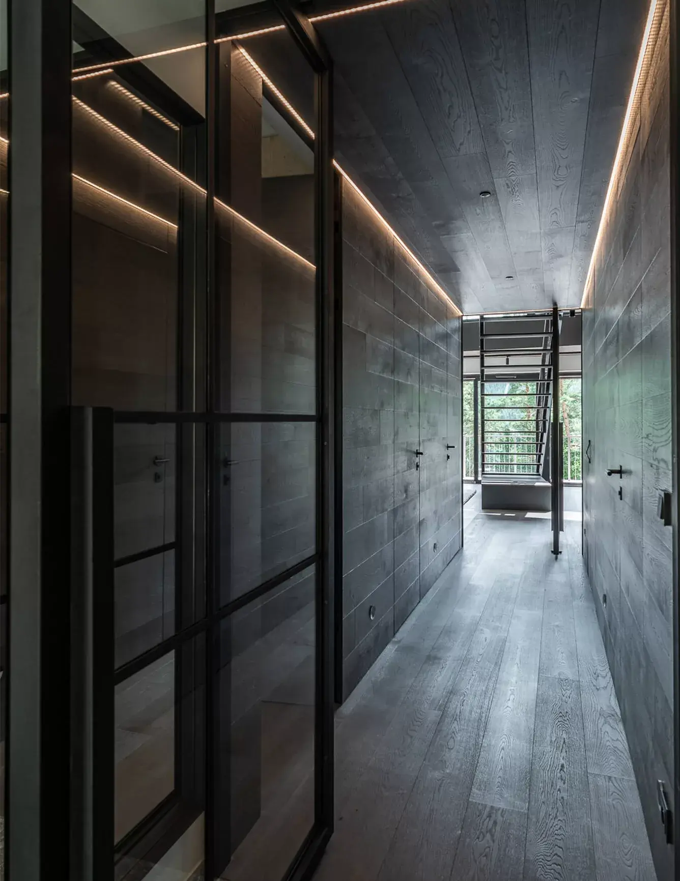 Detail skrytých dveří v apartmánu Lipno s precizně navazujícím tmavě šedým dubovým obkladem stěn Oakcent a minimalistickým černým kováním.