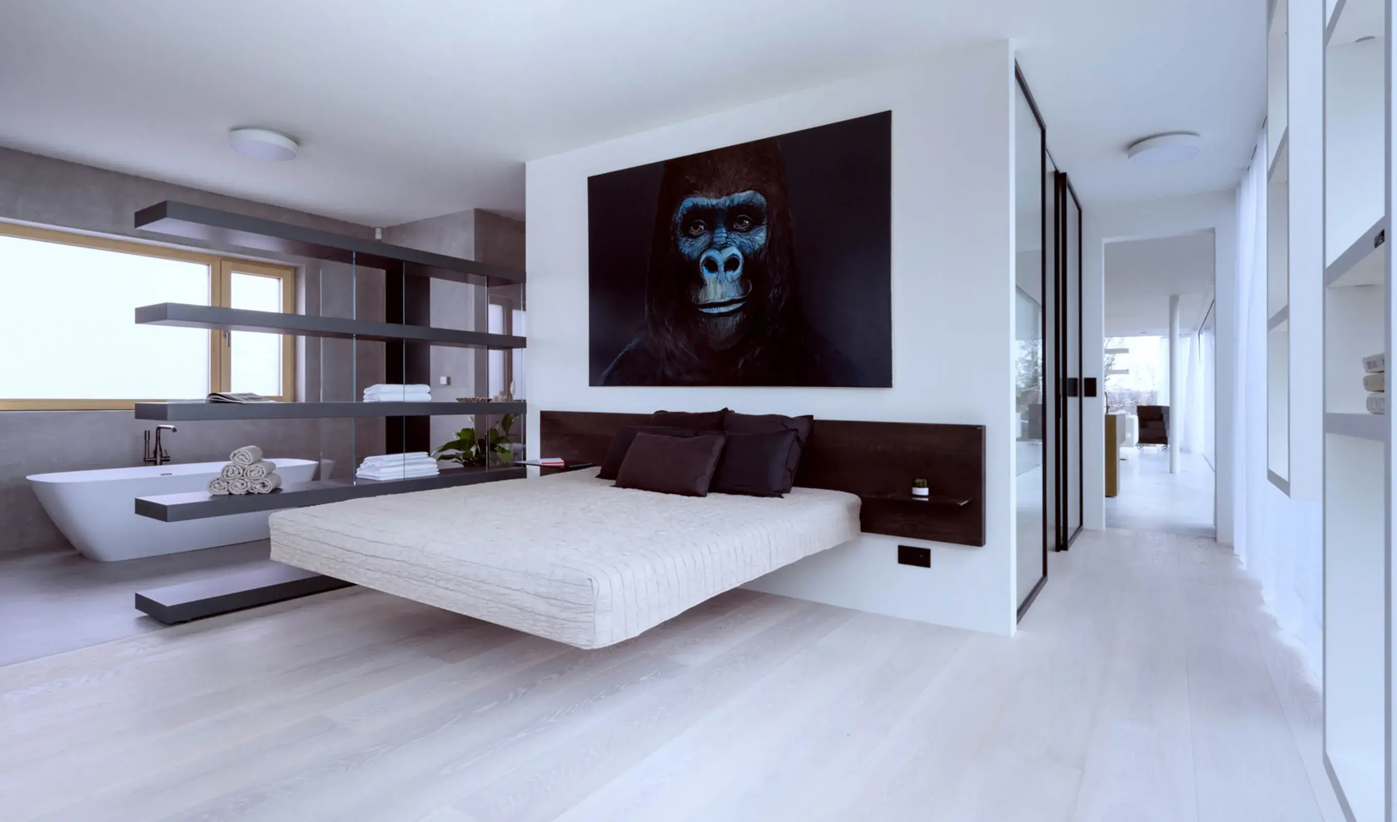 Alt: Širokoúhlý záběr na designovou ložnici v realizaci LAGO Showhouse, kde světlá podlaha z kolekce Ivory prochází pod stylovou levitující postelí a otevřeným policovým systémem, který odděluje prostor od koupelny s volně stojící vanou.