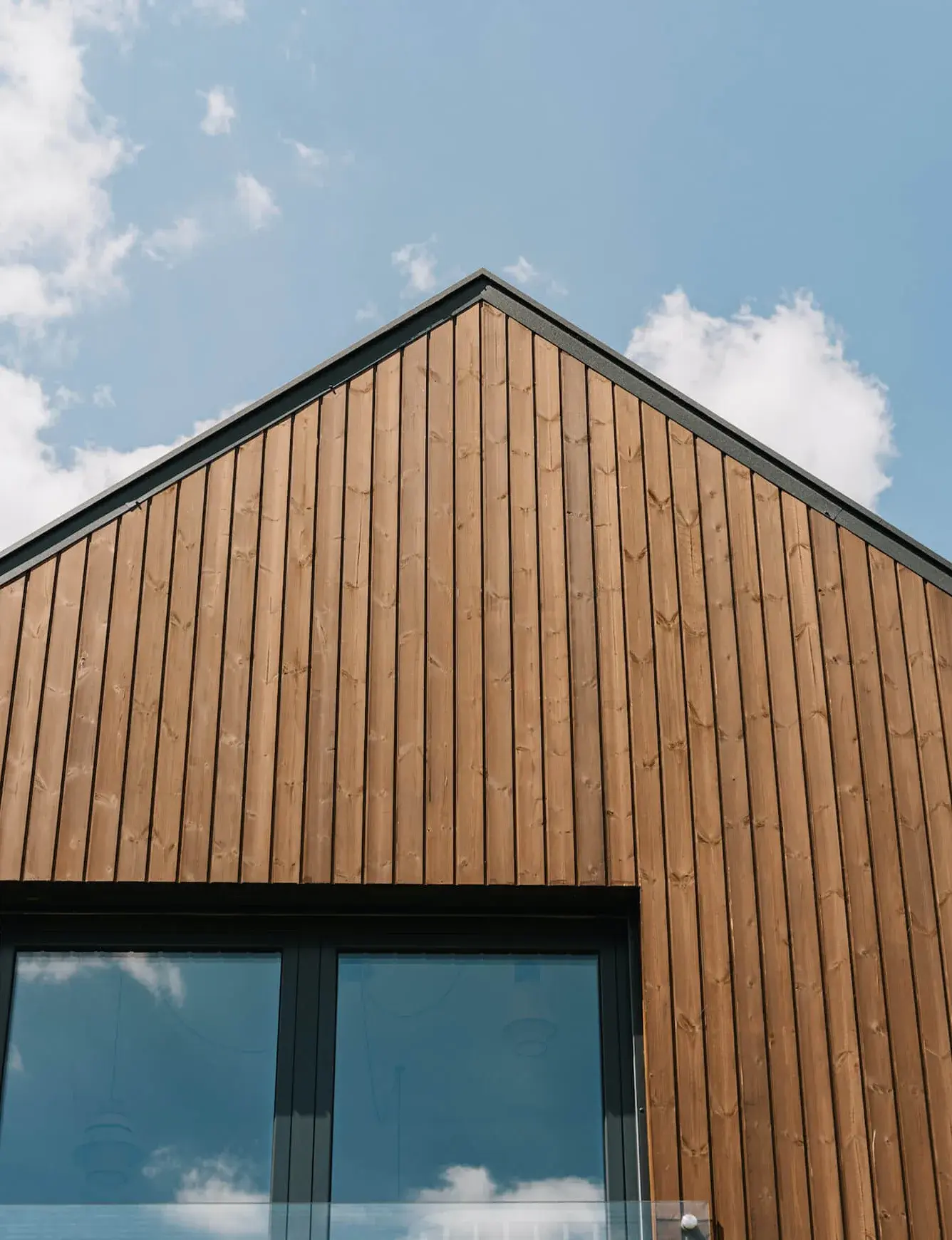 Moderní interiér rekonstruované stodoly v Miloslavě s otevřeným krovem, kde světlá dubová podlaha Oakcent Rustic v odstínu Pure s kartáčovaným povrchem tvoří přirozený základ pro minimalistický prostor s bílou sedací soupravou a černými designovými prvky.