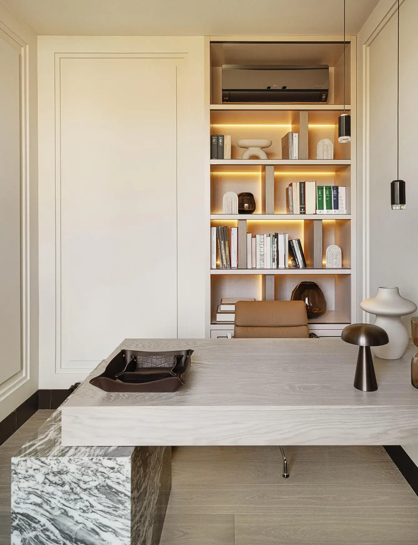 Detailní pohled na luxusní domácí pracovnu v bytě Iwicka ve Varšavě, kde masivní pracovní stůl z běleného dubu s mramorovou podnoží doplňuje vestavěná knihovna s teplým LED podsvícením a dubová podlaha Oakcent Premium v dekoru Milky.