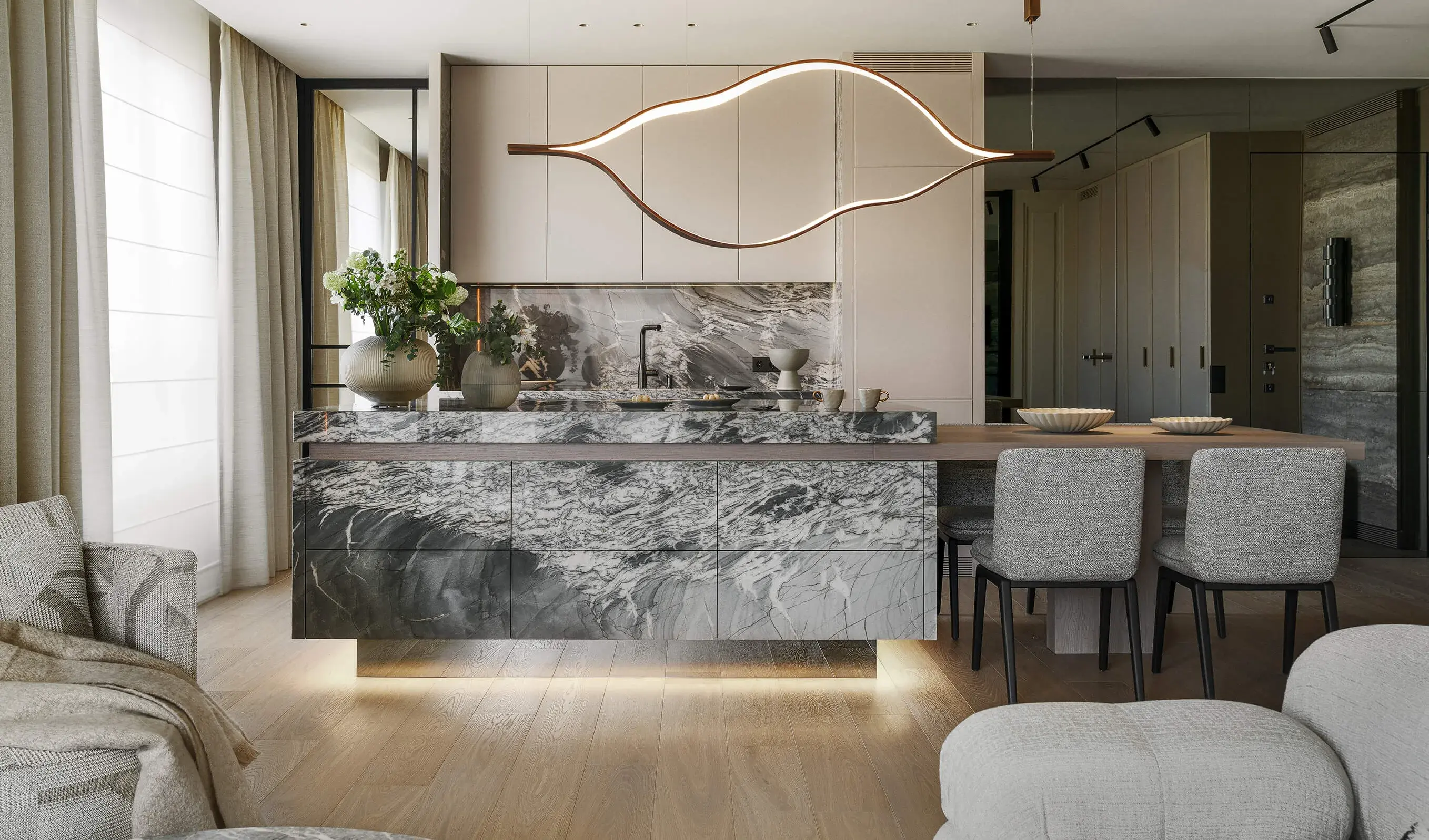 Širokoúhlý záběr luxusní kuchyně v bytě Iwicka, kde dominuje masivní mramorový ostrůvek s výraznou kresbou a integrovaným osvětlením u země, nad nímž visí designové organické svítidlo, vše v harmonii s dubovou podlahou Oakcent Premium Milky.