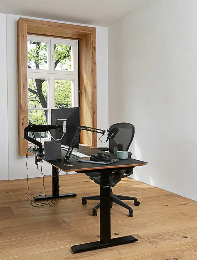 Moderní domácí pracovna v apartmánu Moskal s polohovatelným černým stolem a profesionální technikou, umístěná na dubové podlaze Oakcent Rustic v