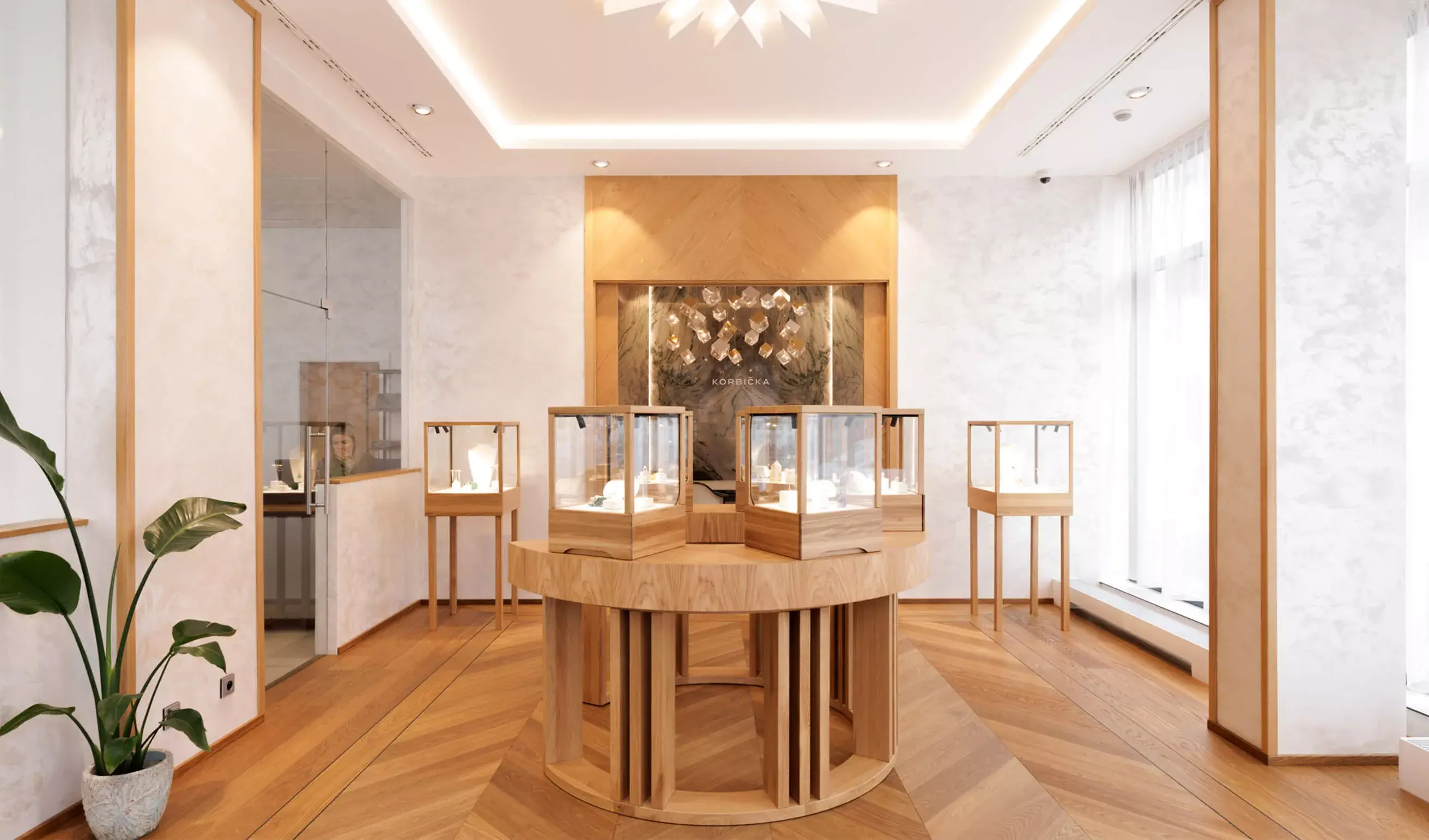 Prosvětlený interiér showroomu šperků Luboše Korbičky v Brně s přírodní dubovou podlahou Oakcent Premium v dekoru Chevron, kterou doplňují elegantní skleněné vitríny na masivních dřevěných podstavcích a minimalistické bílé stěny s jemnou texturou.