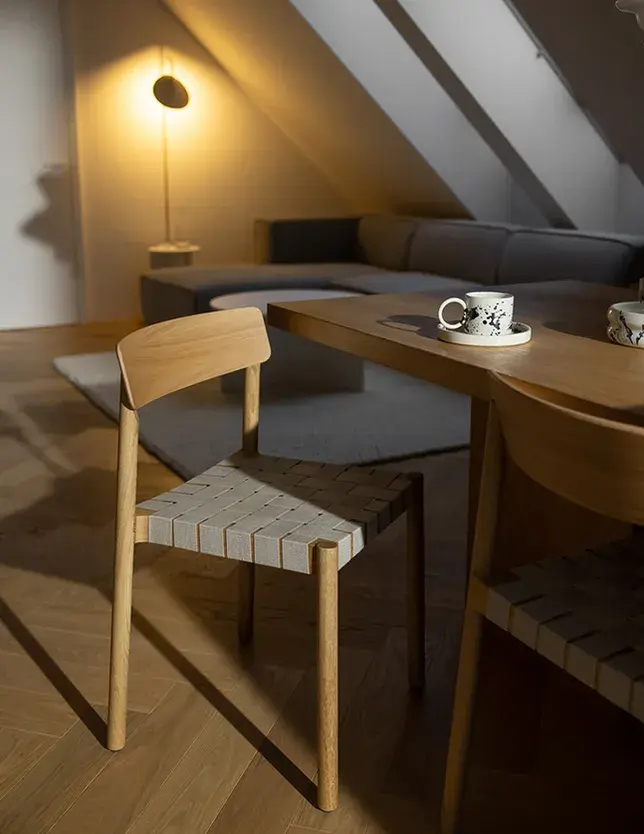 Detail ložnice v olomouckém podkrovním bytě od Cojocarů Architekti, kde se snoubí moderní prvky jako terrazzo obklad stěny a minimalistické bílé doplňky s teplým odstínem dubové podlahy Oakcent položené do vzoru rybí kosti.