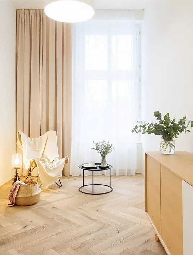Interiér světlého pokoje v brněnském bytě, kde dubová podlaha Oakcent Rustic ve vzoru Herringbone a odstínu Light White ladí s minimalistickým nábytkem, krémovými závěsy a jemným přírodním světlem z velkého okna.