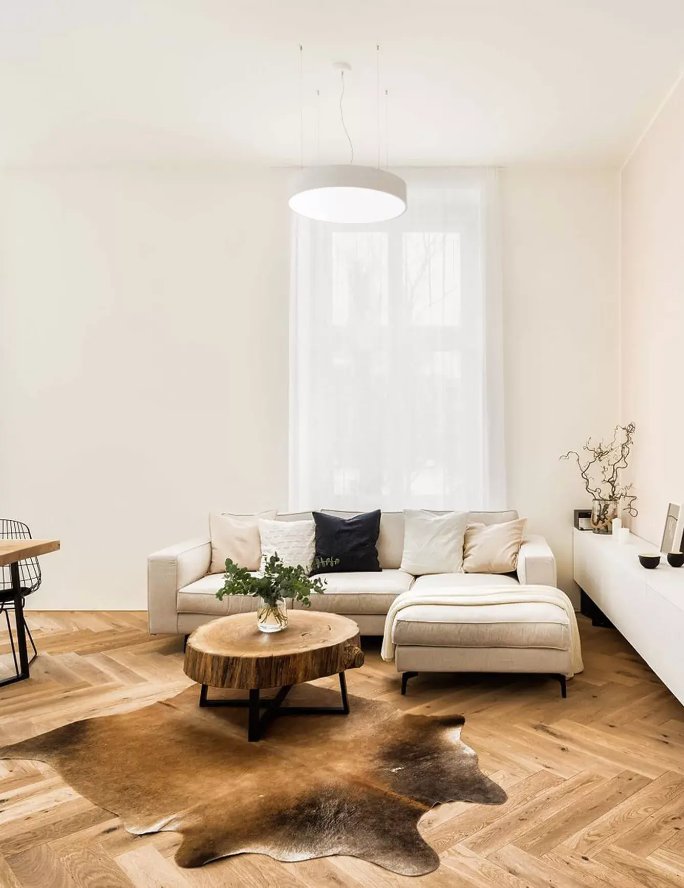 Interiér světlého obývacího pokoje v brněnském neorenesančním domě u Lužáneckého parku, kde dubová podlaha Oakcent Rustic ve vzoru Herringbone doplňuje moderní světlou pohovku, konferenční stolek z masivního kmene a kůži na podlaze.