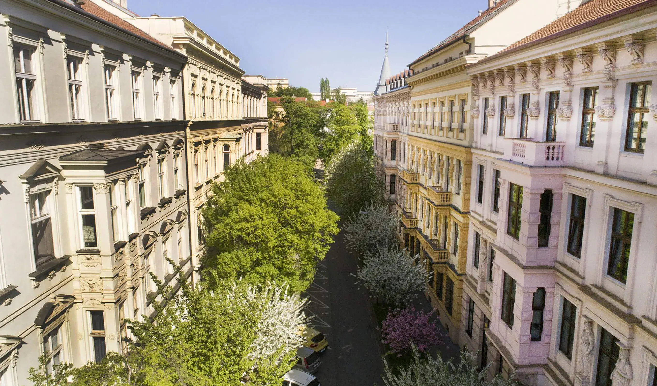 Letecký pohled na řadu historických činžovních domů u Lužáneckého parku v Brně, ilustrující kontext rekonstrukce s cílem zachovat genius loci místa.