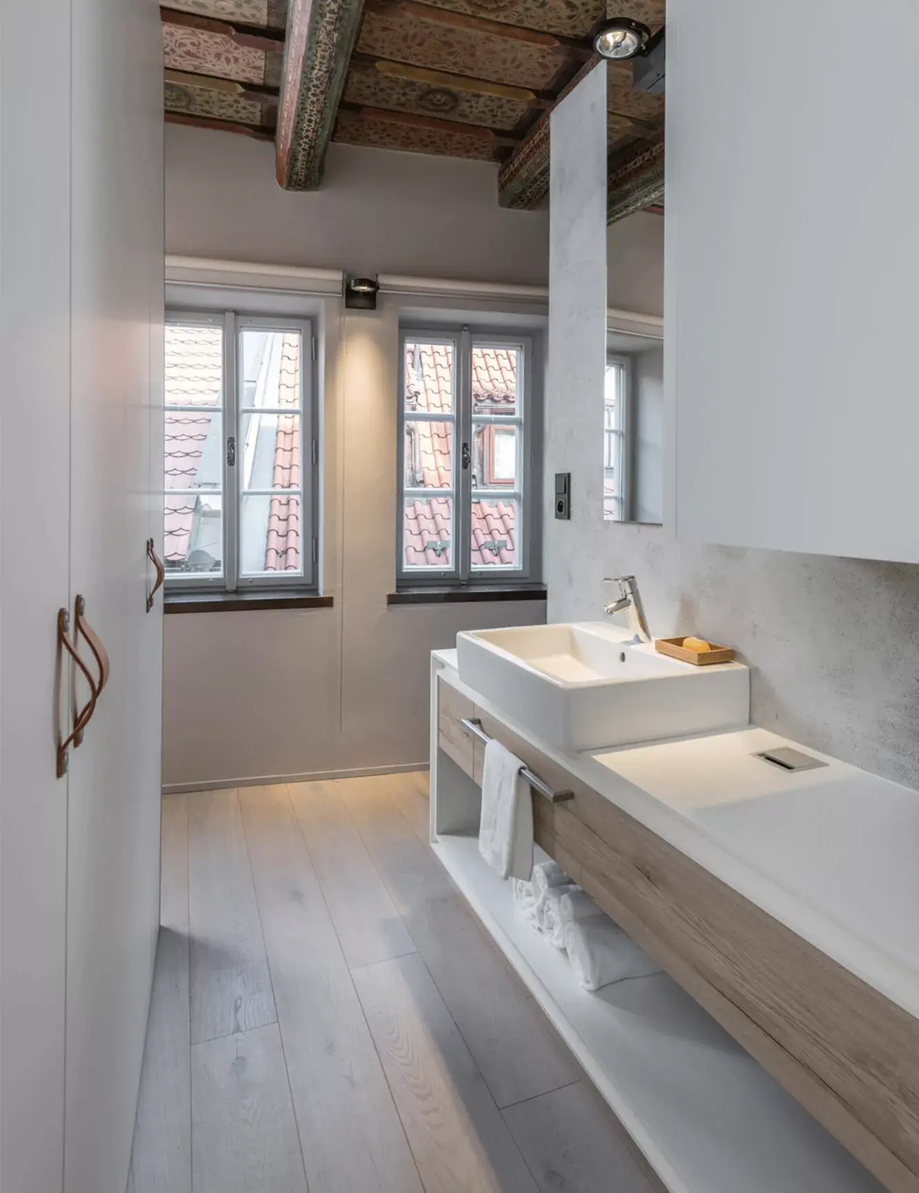 Moderní koupelna v historickém bytě na Malé Straně s dvojumyvadlem na dřevěné desce, světlou dubovou podlahou Oakcent a výhledem na pražské střechy.
