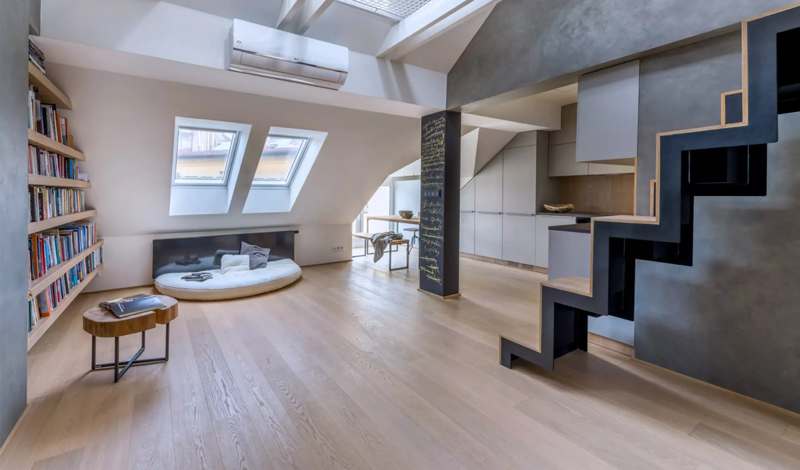 Interiér otevřeného podkrovního bytu Karlínské útočiště se schodištěm a podlahou z dubových prken Oakcent Sand, která jsou použita i jako obklad v kuchyni pro optické sjednocení a zvětšení prostoru.