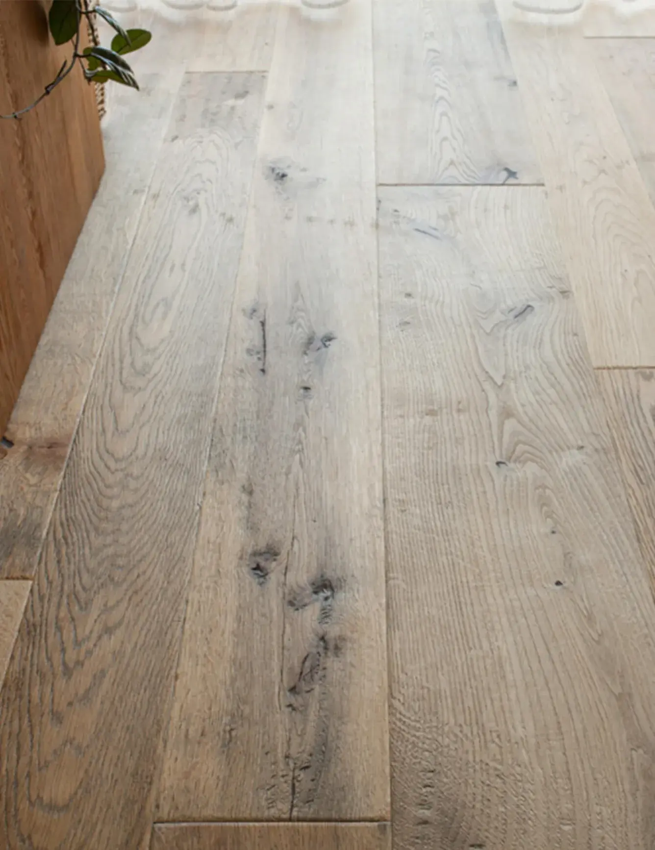 Detailní záběr na texturu dubové podlahy Oakcent Rustic v Uherském Hradišti, která díky louhování, bělení a ošetření Nano olejem získala unikátní světlý vzhled s výraznou kresbou dřeva a přiznanými suky.