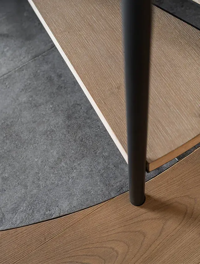 Detailní záběr na precizní napojení dřevěné podlahy Oakcent na kruhovou břidlicovou podestu pod točitým schodištěm, ilustrující plynulé propojení materiálů v interiéru Domu nad rybníkem.