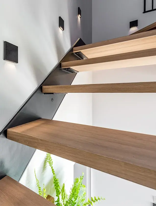 Detail schodiště s otevřenými dubovými stupni OAKCENT a subtilní černou ocelovou konstrukcí, které doplňuje prosvětlený interiér domu v Tyniec Mały a podtrhuje jeho sofistikovanou, hřejivou atmosféru.