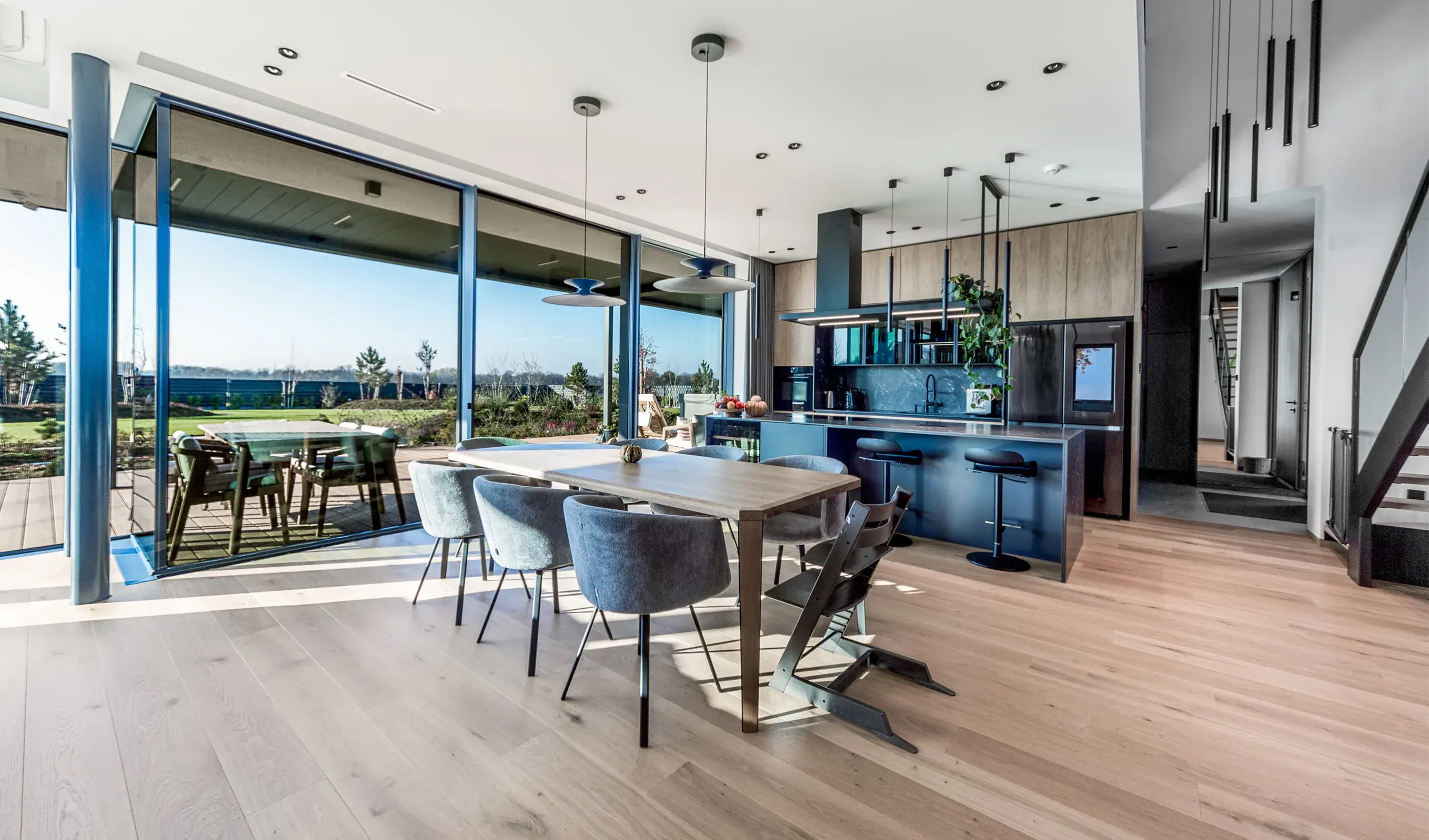 Panoramatický pohled na velkorysý obývací prostor v Tyniec Mały, kde 2,2 metru dlouhá dubová prkna Oakcent Rustic v odstínu Pure opticky zvětšují místnost a v kombinaci s prosklenou stěnou na terasu vytvářejí vzdušný a nadčasový interiér.